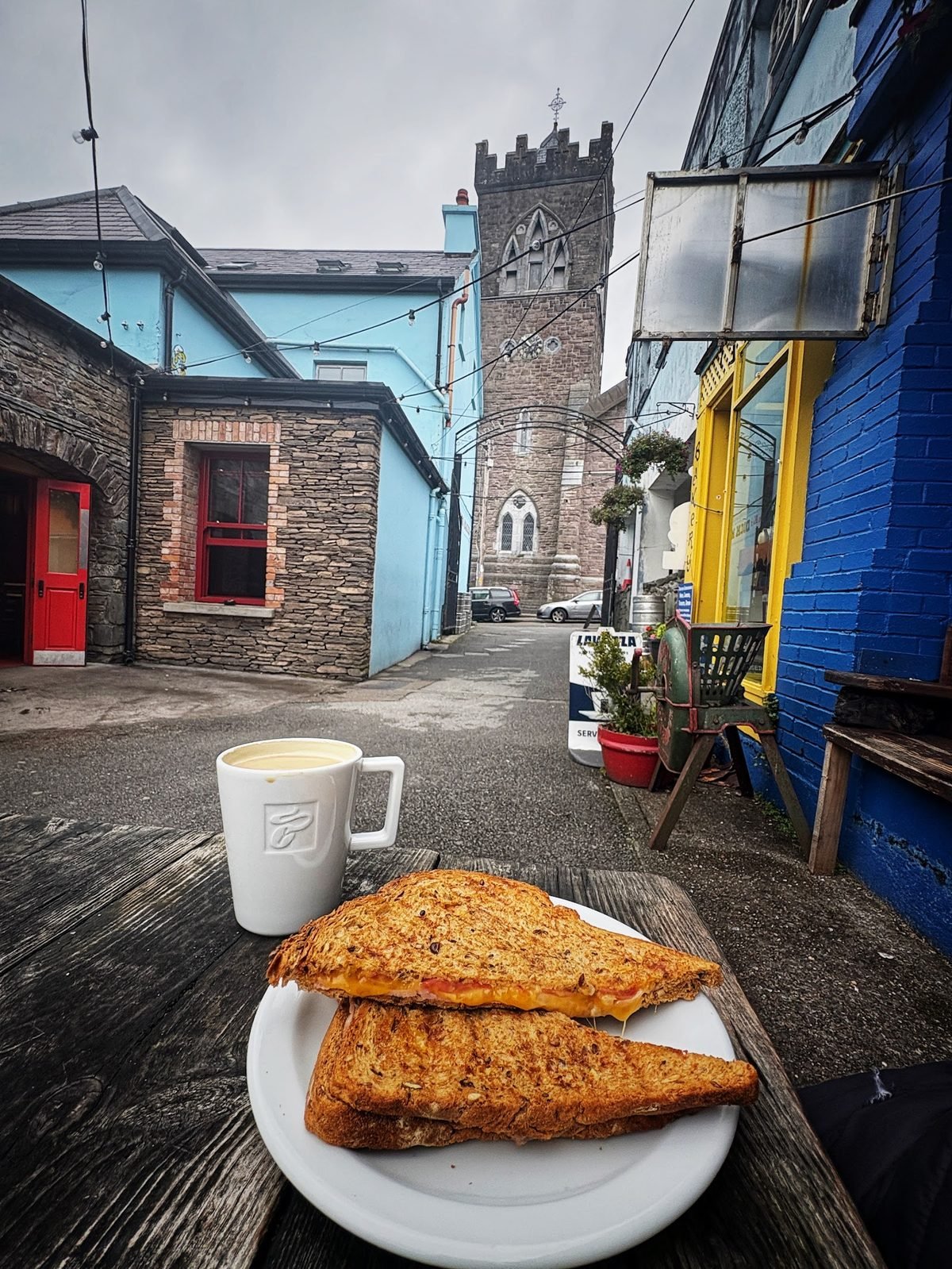Coffee and a toasted sandwich with St Mary's church tower behind in Dingle